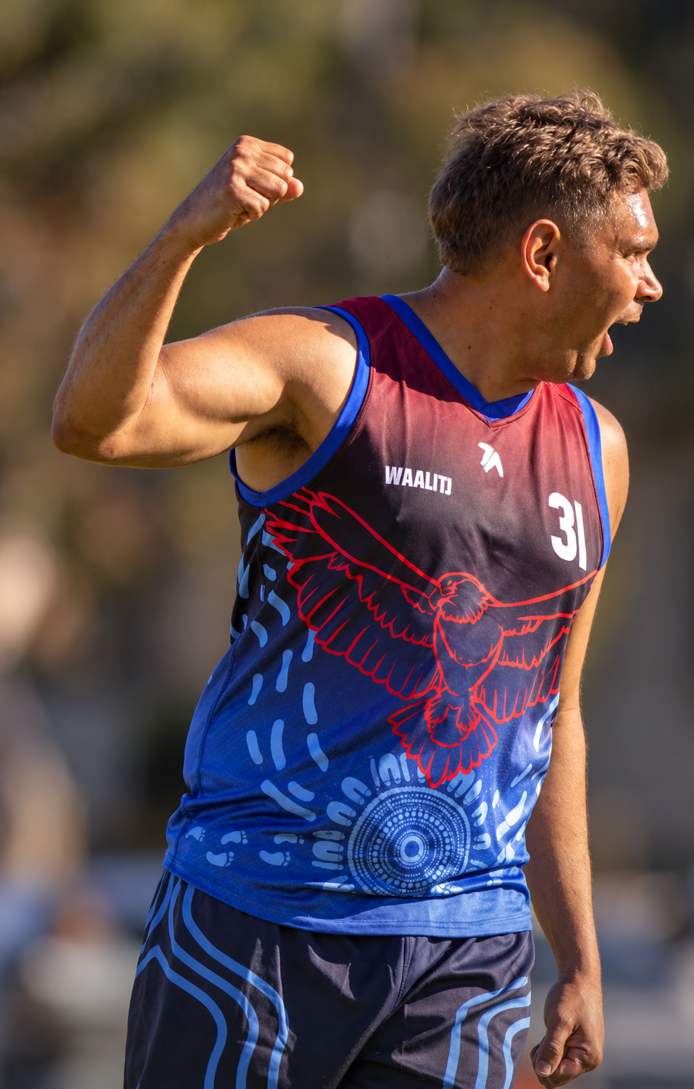 Bunbury Waalitj footballer celebrating with a raised fist while wearing the Dialocal Active carnival kit